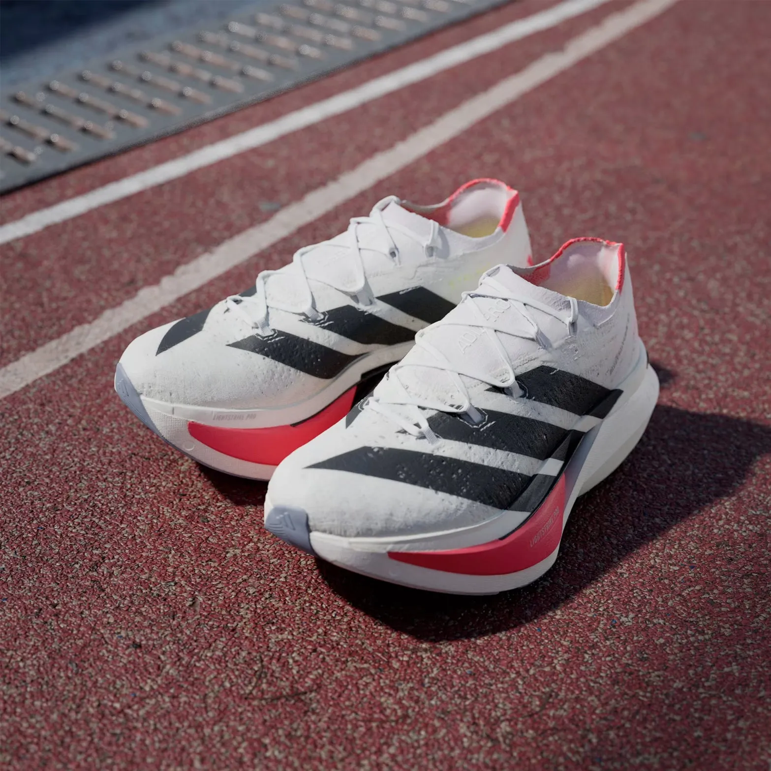 Adizero Prime X 3 Strung Running Shoes Cloud White / Core Black / Lucid Red running in an underpass area shoes